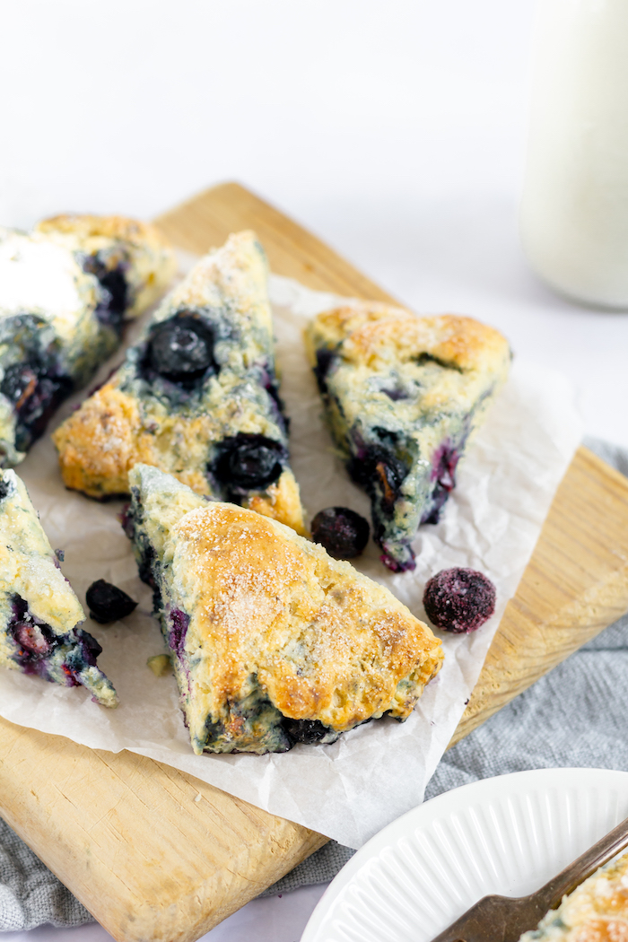 Image shows pieces of blueberry scone on a wooden board