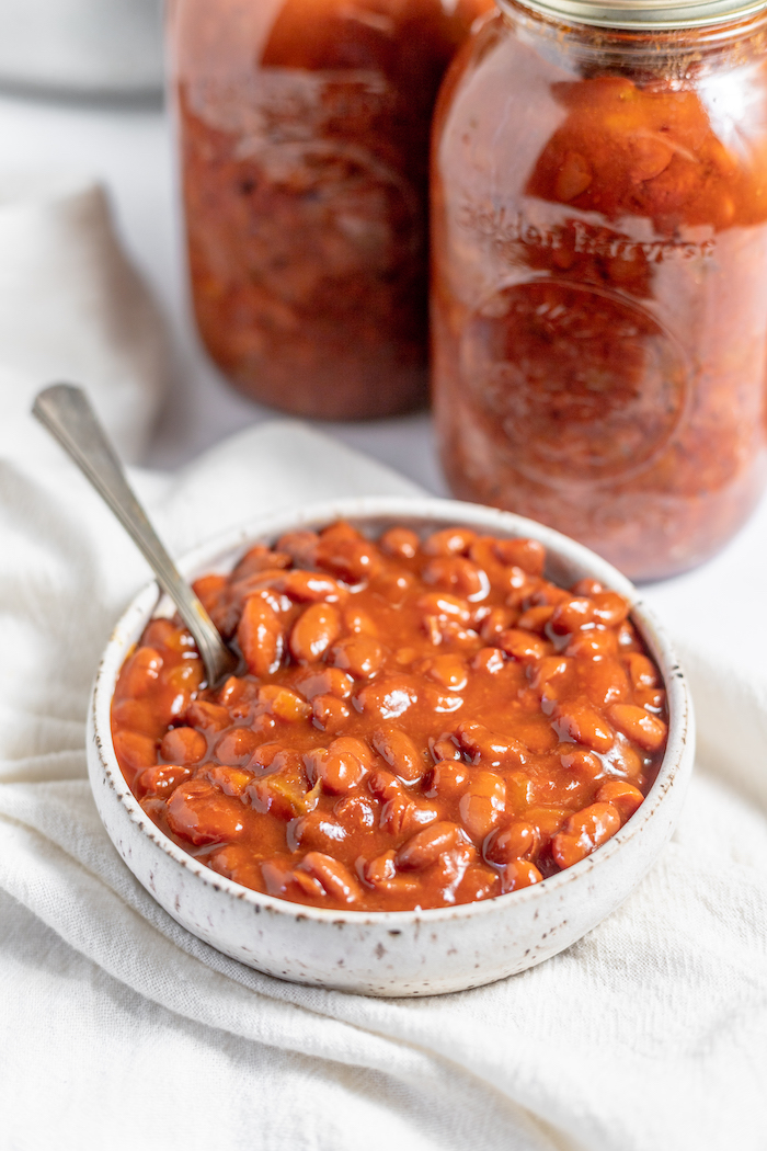 a bowl of home-canned baked beans with jars of beans in the background