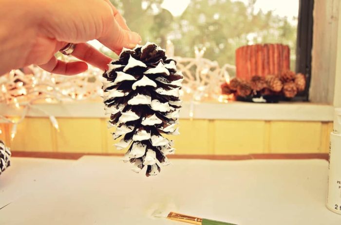 Image shows a hand holding a painted pinecone