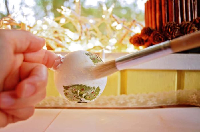 Image shows a hand painting white on a glass ornament
