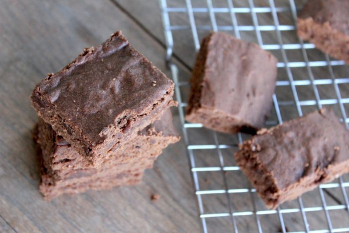 Image shows several chocolate brownies on a table and cooling rack