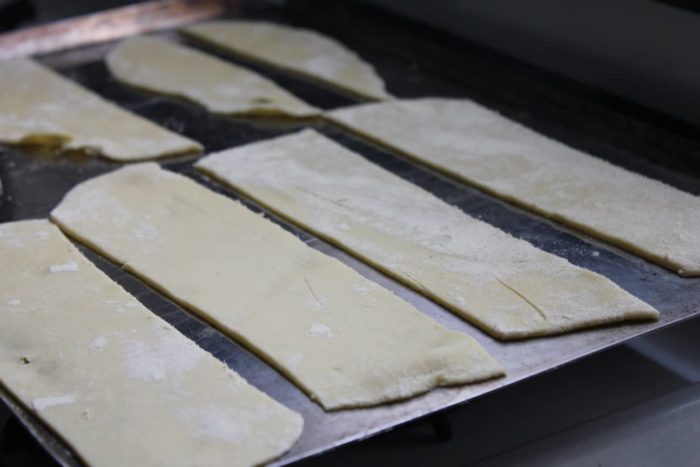 Image shows pasta dough laid out on a pan for baking
