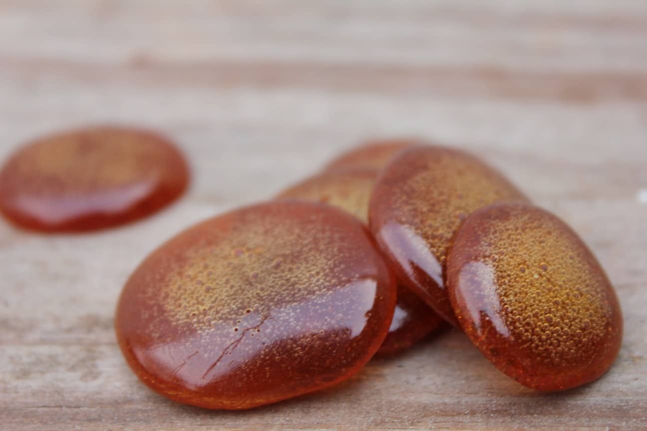 Image shows a close up photo of six brown homemade cough drop stacked on one another