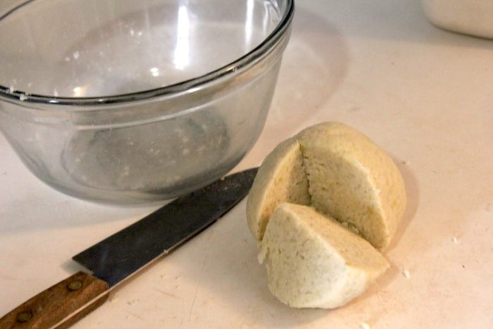 Image shows a glass bowl with a knife and gnocchi dough