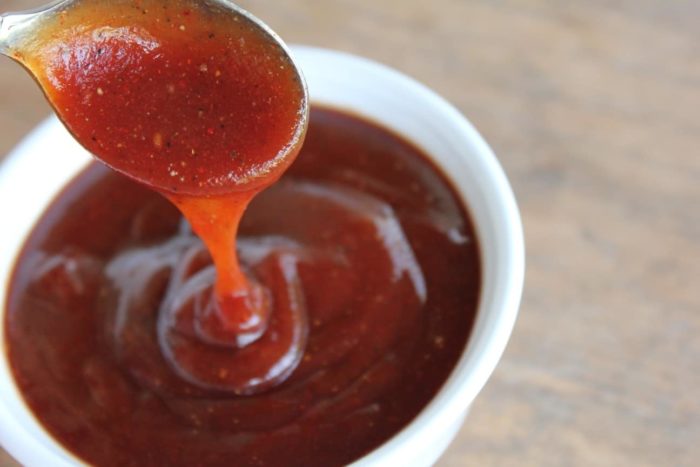 Photo shows a spoon of barbecue sauce over a bowl of sauce