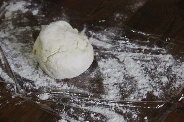 Image shows a ball of dough on some flour