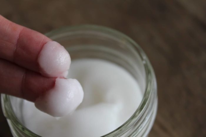 Image shows a small jar with two fingers holding homemade face cream