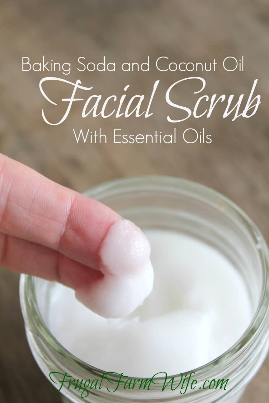 Image shows a jar of white facial scrub in the background, two fingers with scrub on the tips are posed above the jar, text above reads "Baking Soda and Coconut Oil Facial Scrub with Essential Oils"