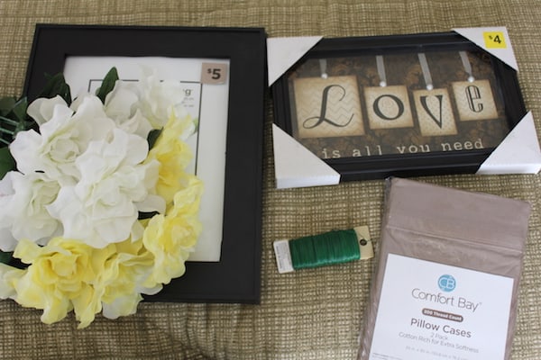 Image shows supplies needed for a budget bedroom makeover, silk flowers, frames, pillow cases