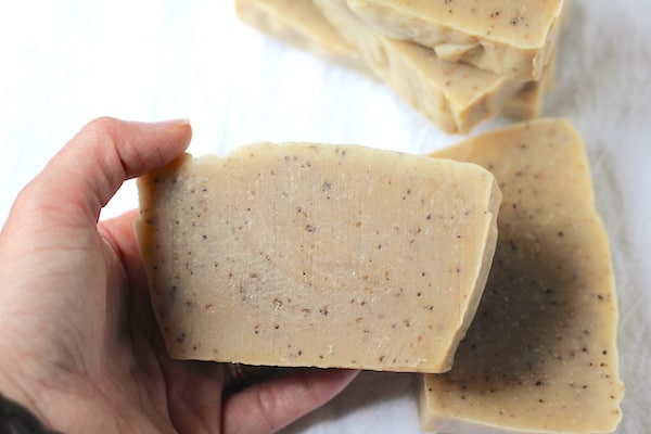 Photo shows a hand holding a bar of coffee scrub soap