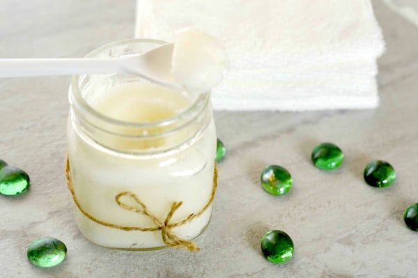 Photo shows a jar of sugar scrub with a white spoon on top
