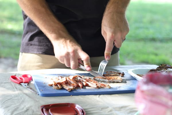 Image shows a man slicing pork with a fork and knife