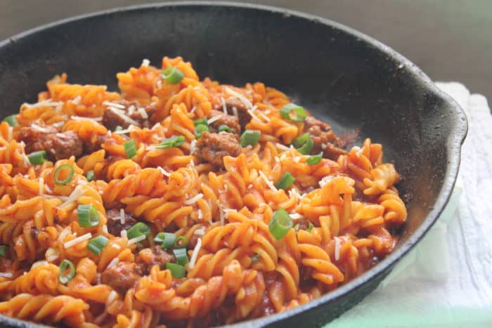 Image shows a skillet of noodles with meat