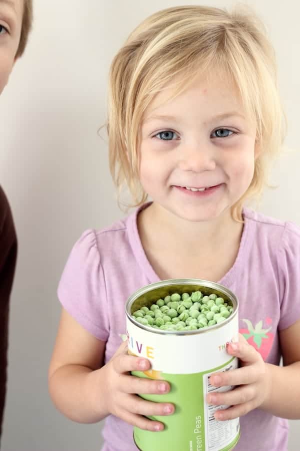 Image shows a little girl holding a can of freeze dried peas