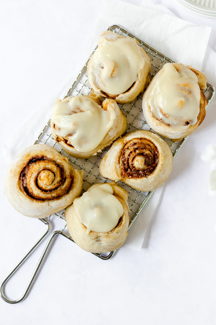 Image shows a wire rack holding six cinnamon rolls