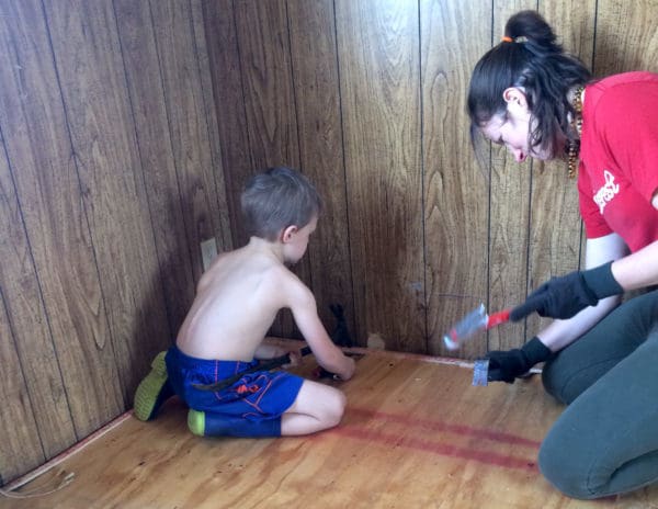 Image shows a woman and a small boy hammering down some flooring in an RV.