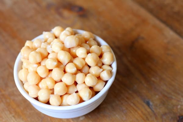 Image shows a bowl of chick peas on a table