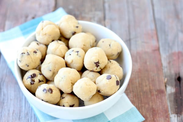 Photo shows a bowl of chocolate chip cookie dough protein balls on a table