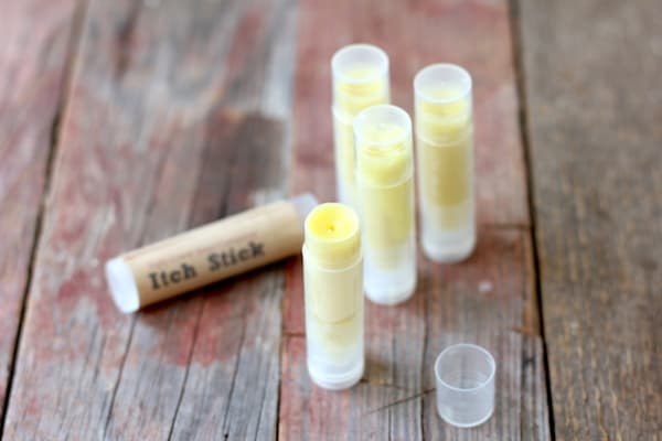 Image shows several tubes of homemade itch stick standing on a table. The one in front has its cap removed.