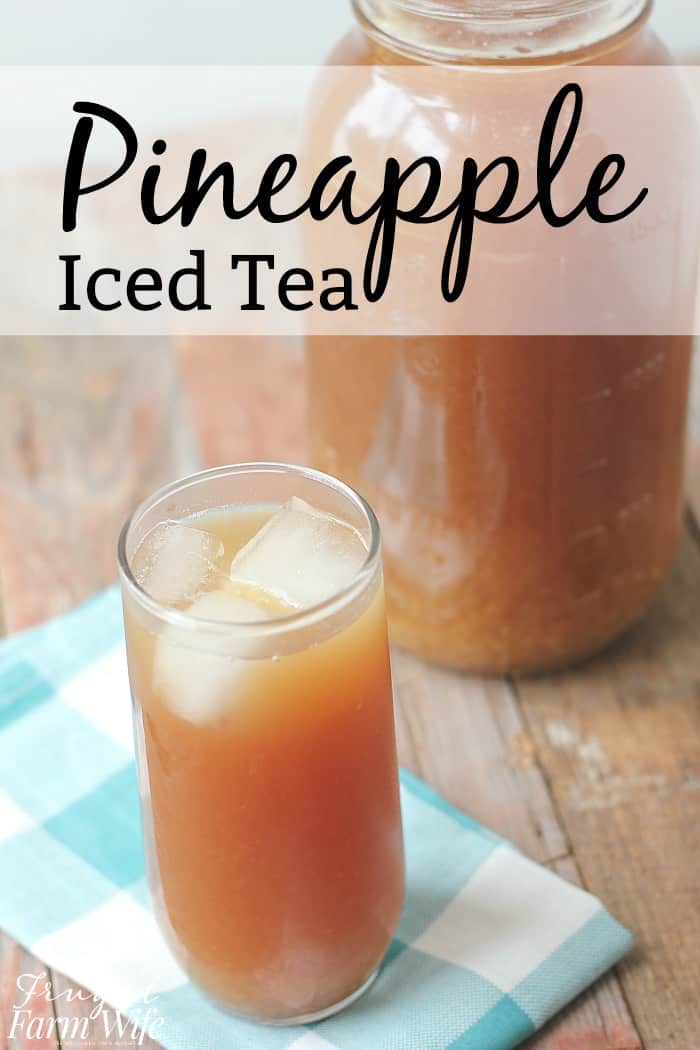 Image shows a glass of pineapple iced tea with ice cubes, in front of a large mason jar of more pineapple iced tea. Text overlay reads "Pineapple Iced Tea"