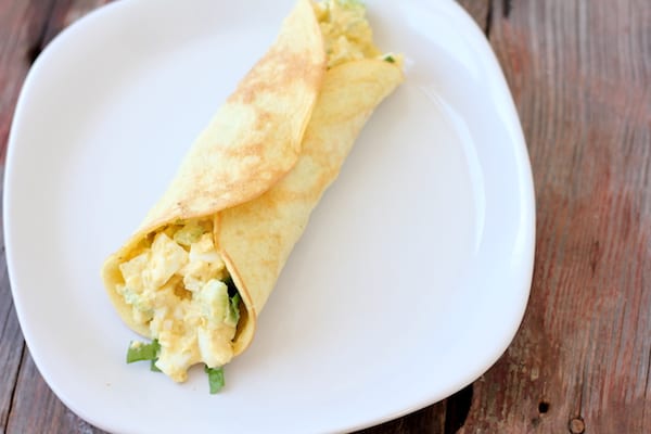 Images shows an egg salad wrap with lettuce on a white plate