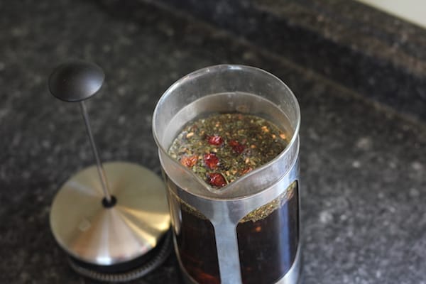 Photo shows a press filled with immune boosting tea on a dark countertop