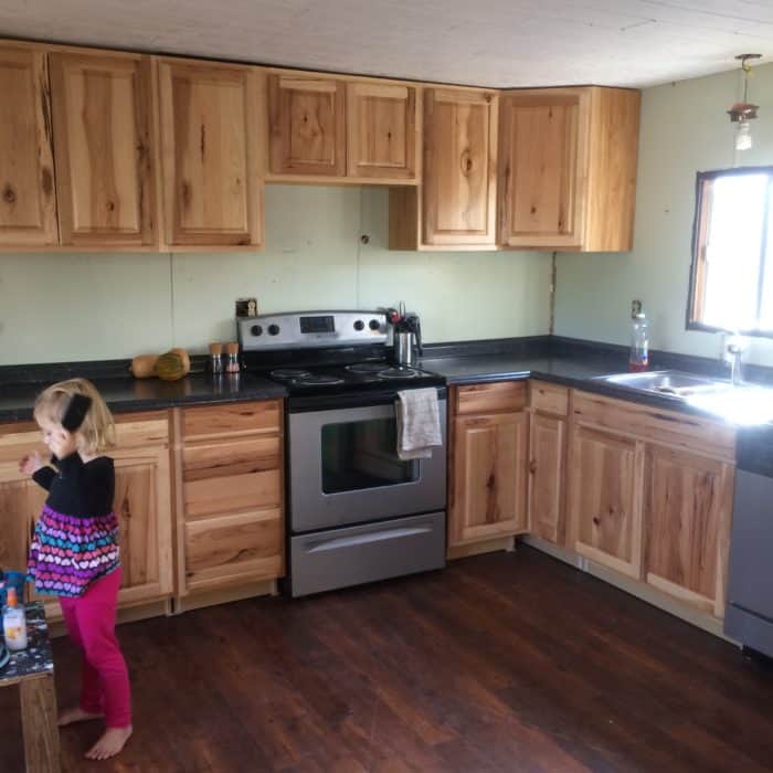 Photo shows a young girl playing in a kitchen with updated cabinets