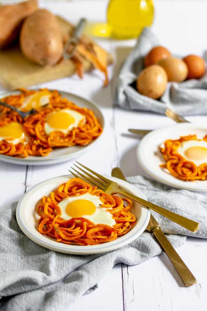 Photo shows several plates of spiralized sweet potatoes cooked with eggs