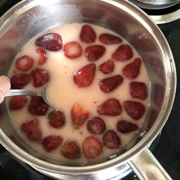 Image shows a pot of strawberries boiling to make syrup