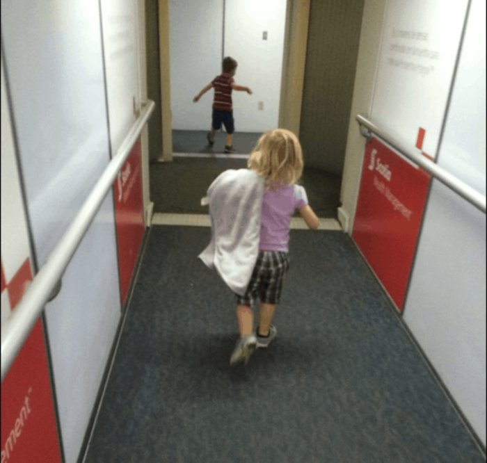 Photo shows two small children running down the jetway to an airplane