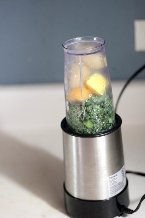 Image shows a small blender with ingredients for a green smoothie
