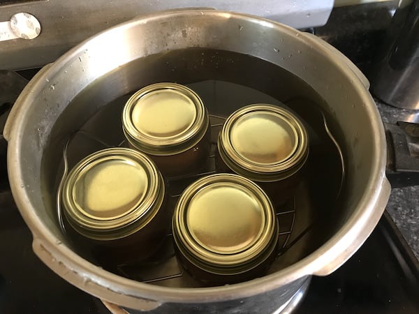 Picture shows jars of pear sauce in a pot of hot water
