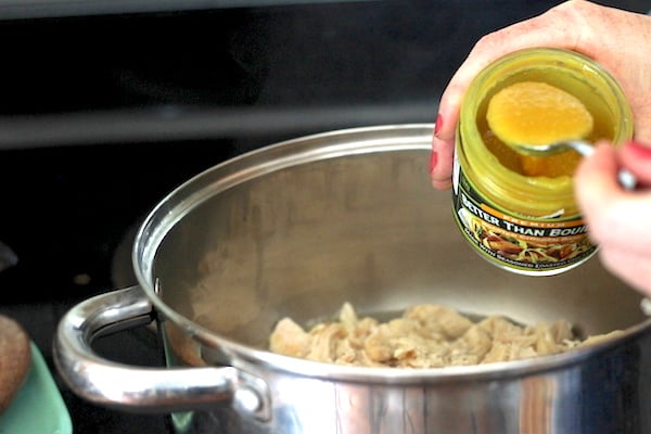 Image shows a hand adding chicken base to the soup