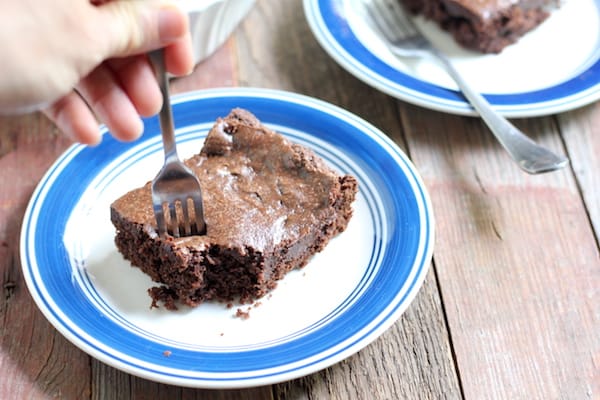Photo shows a fork taking a bit of chocolate cake on a white and blue plate