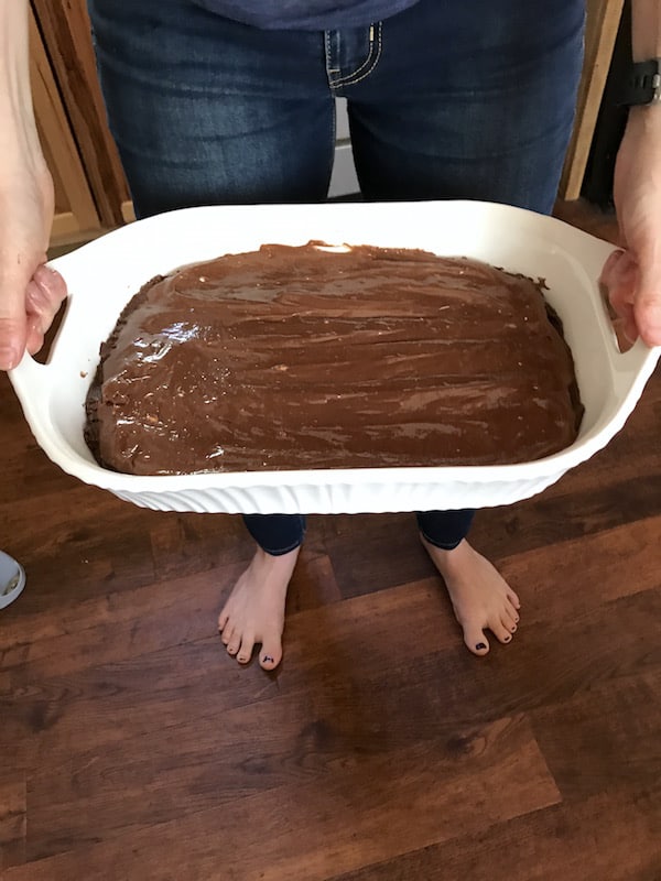 Photo shows a woman holding the pan of batter ready for the oven 