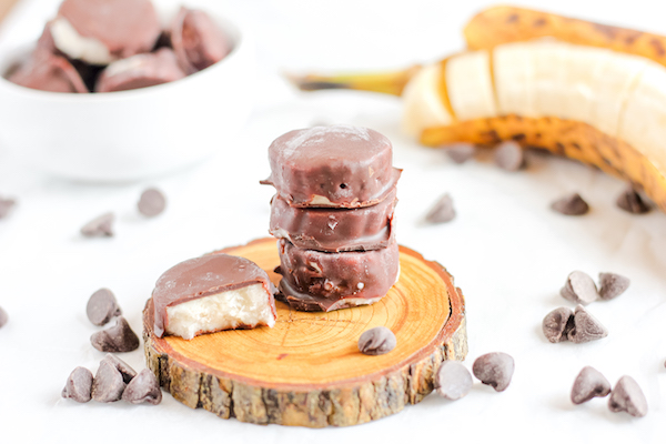 Image shows several chocolate-covered banana bites stacked