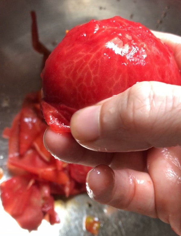 Picture shows a hand peeling a tomato