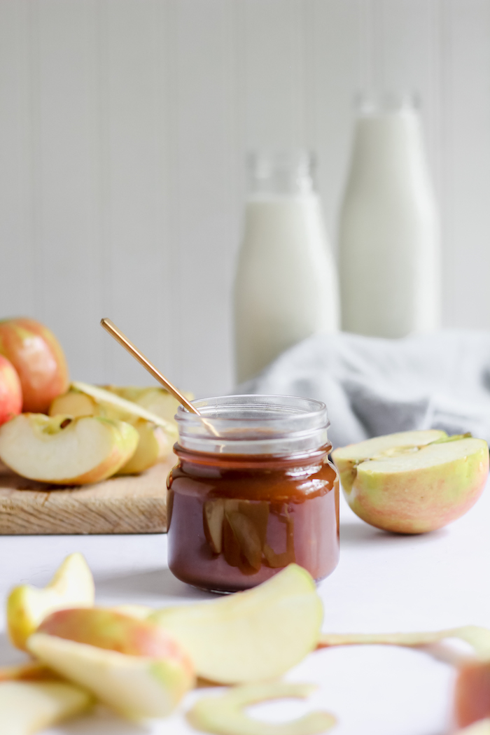 Photo shows a jar of caramel sauce on a white table 