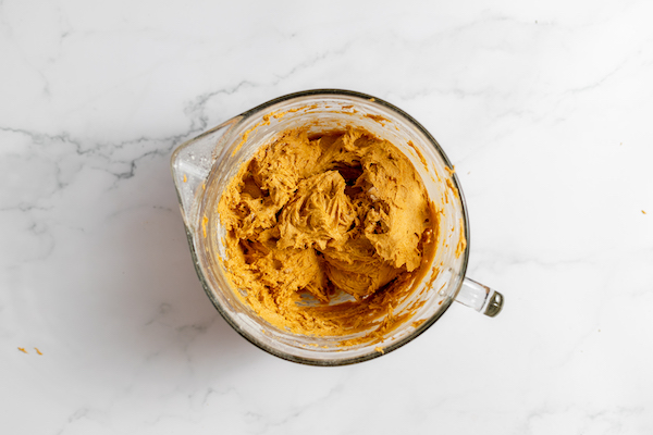 Image shows gluten free pumpkin cookie batter in a glass mixing bowl ready to bake