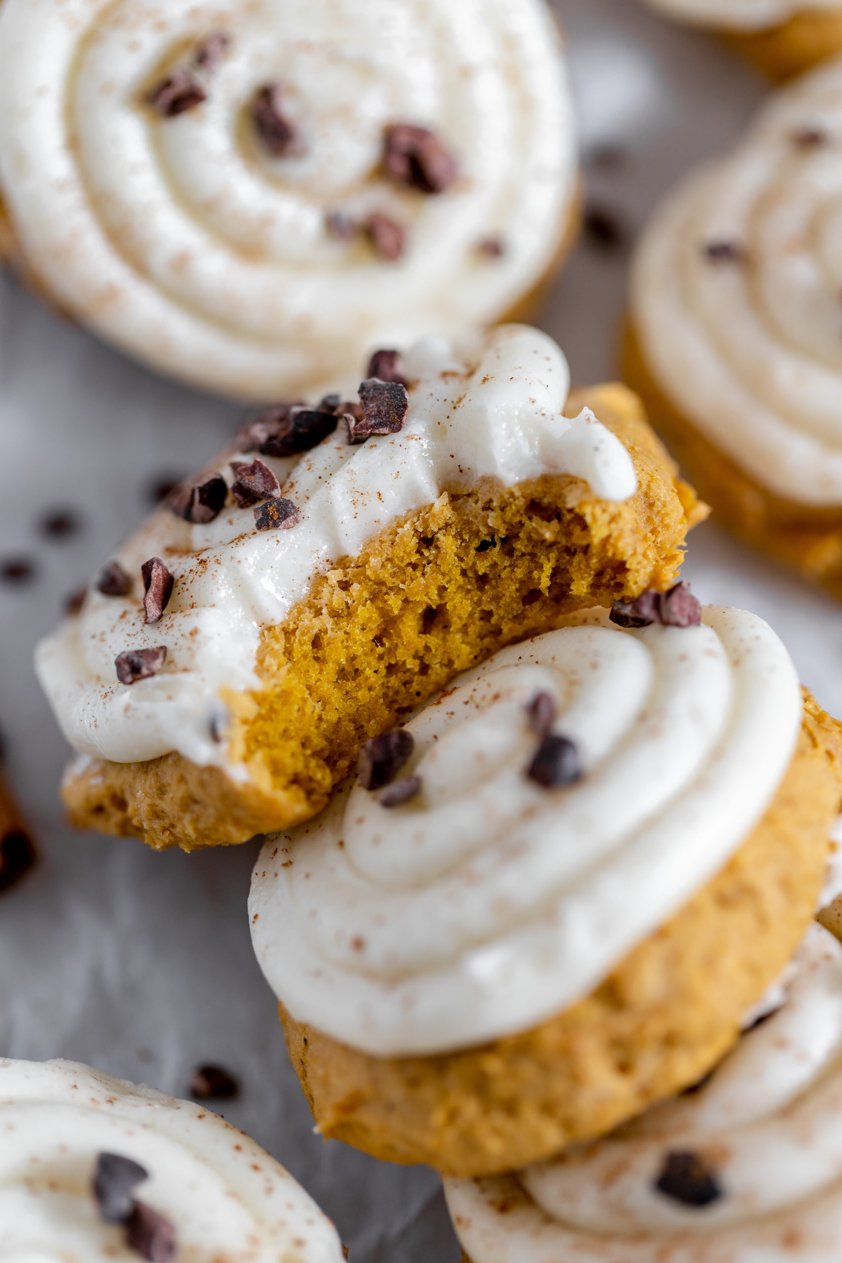 Image shows a close up of gluten free pumpkin cookie with icing and cacao bits