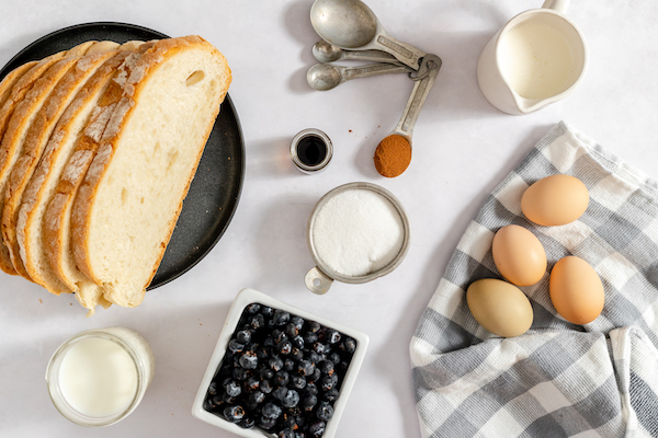 gluten free bread, blueberries, milk, sugar, eggs, and spices on a table