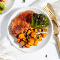 sheetpan pork chops with sweet potatoes and broccoli on a plate.