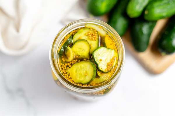 jar of pickles on a counter with cucumbers