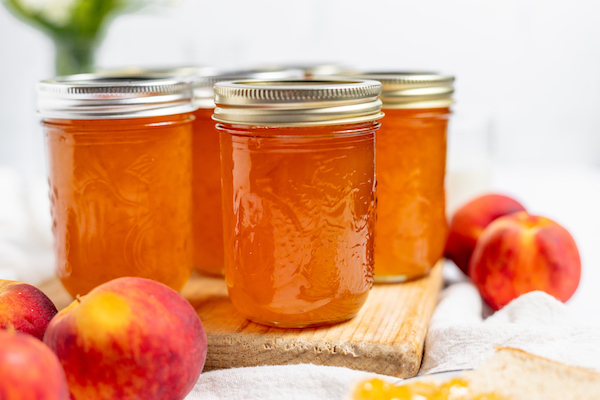 jars of peach jam on a white surface